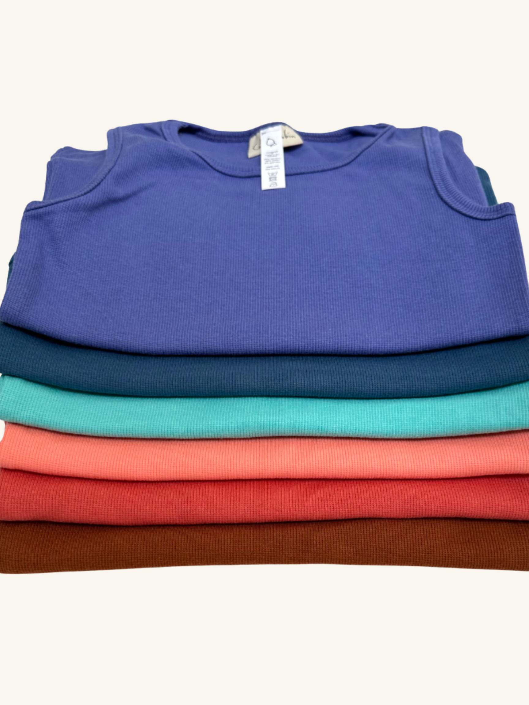 Stack of folded shirts in blue, green, red, and brown on a white background