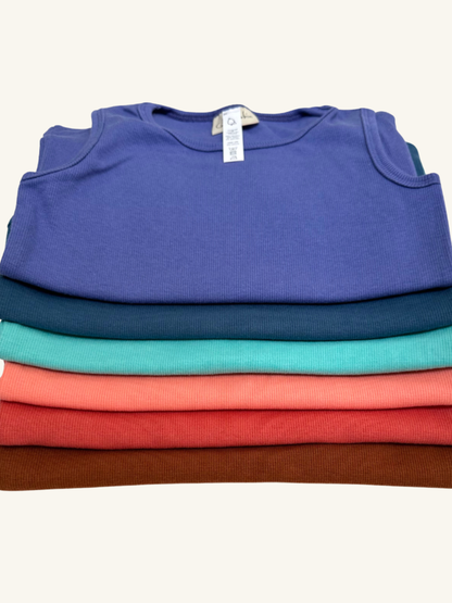 Stack of folded shirts in blue, green, red, and brown on a white background